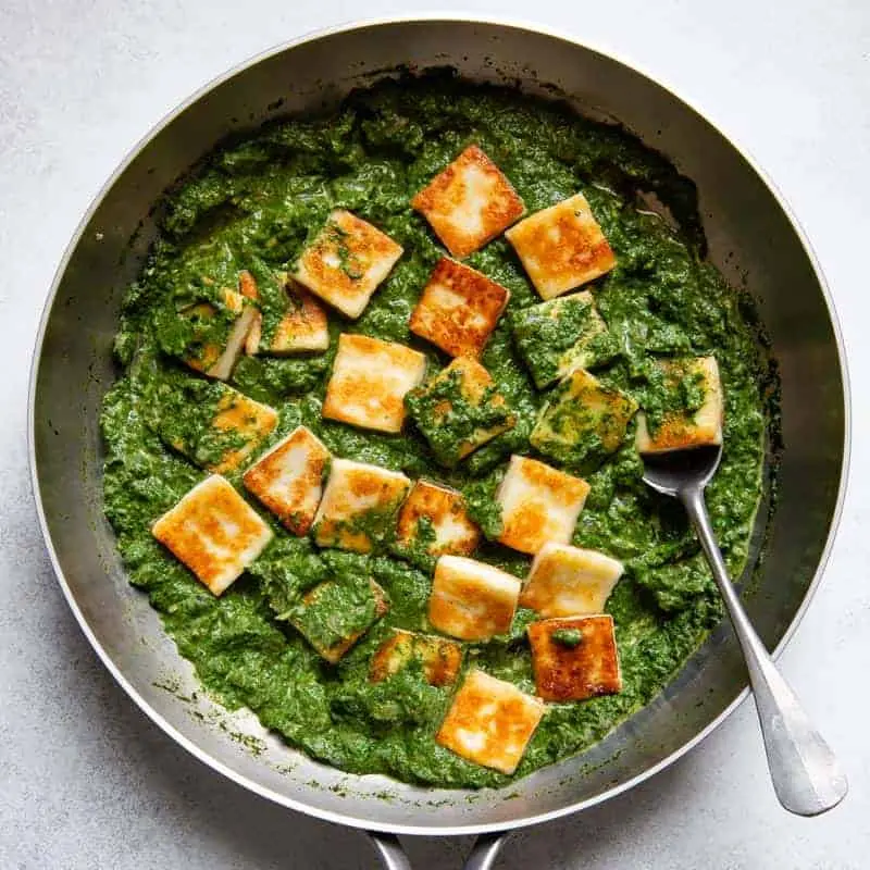 A plate of creamy palak paneer garnished with fresh coriander leaves.